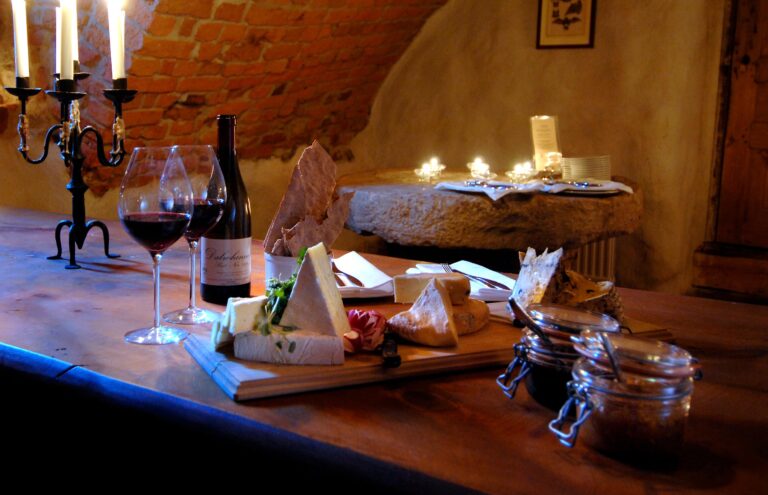 En ostbricka och två glas rödvin på ett bord i en vinkällare