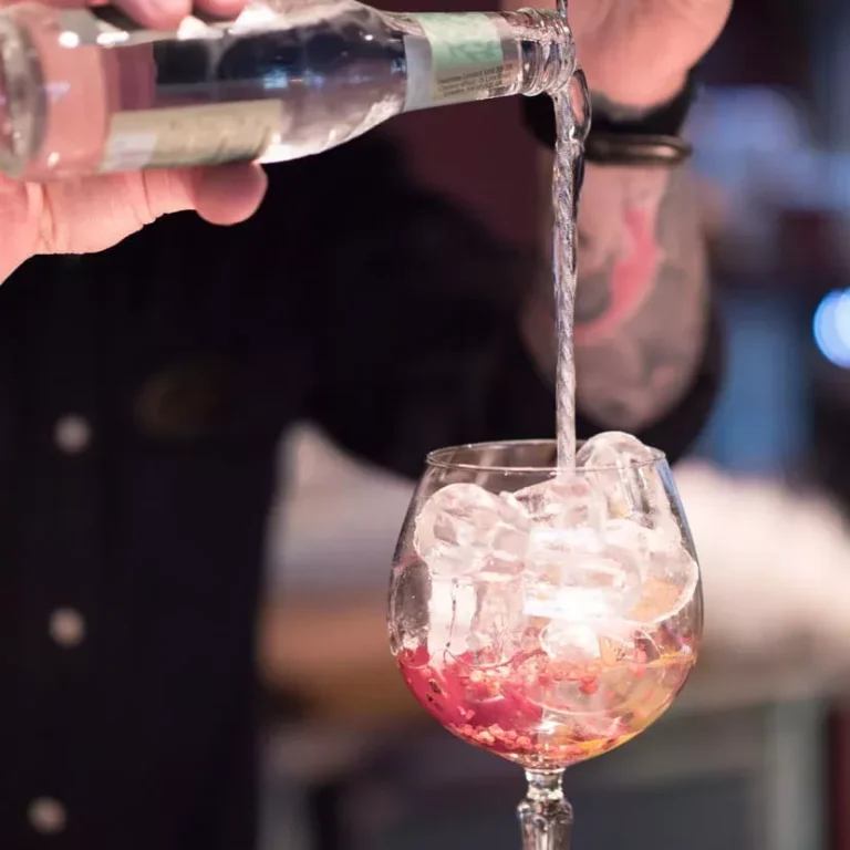 En bartender häller upp en drink i ett glas med is